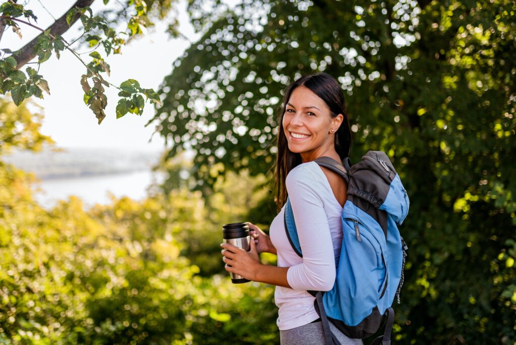 Portrait of a positive young woman on a hike near the river.